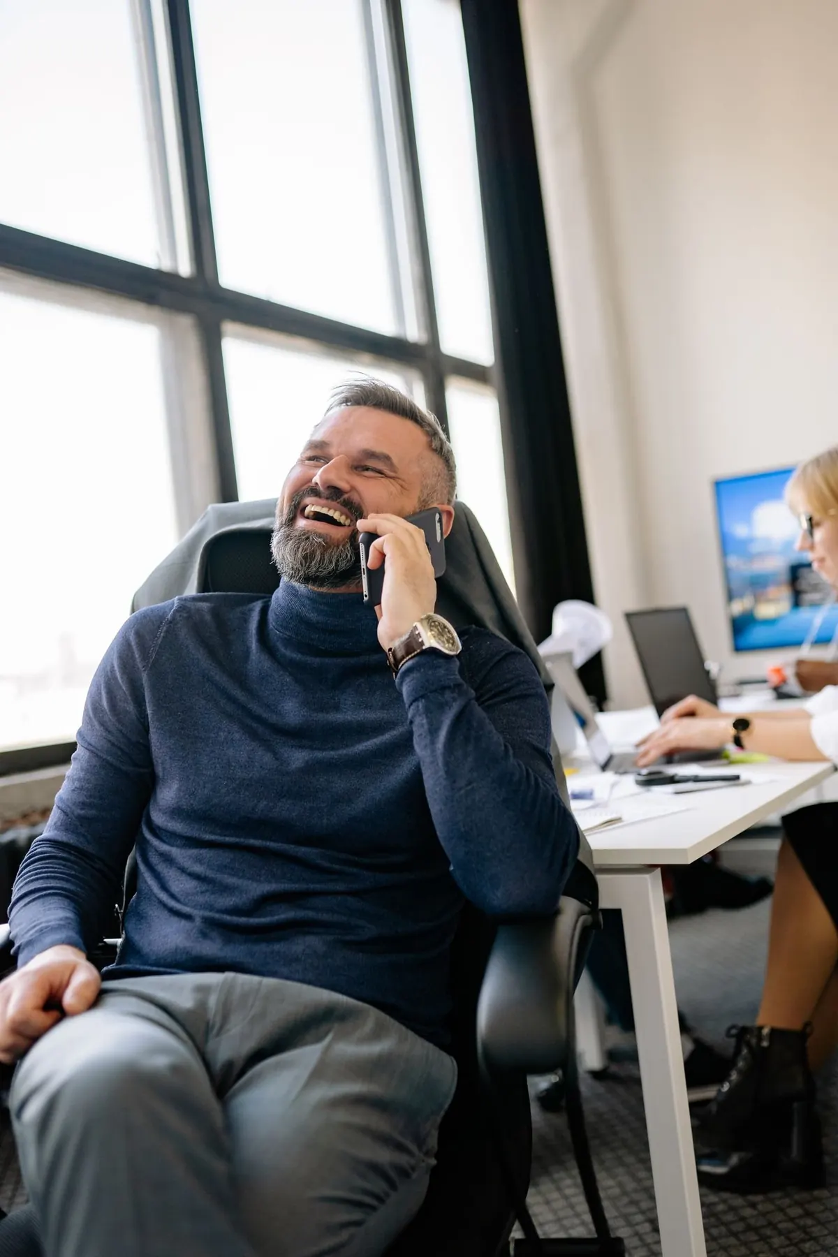 Dirigeant qui rit au téléphone dans son bureau